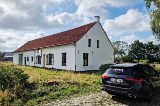 Plan large d'une ferme blanche avec un toit brun à Putte