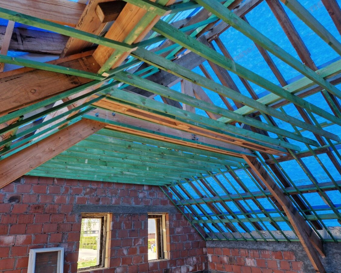 Toiture en chantier avec charpente en bois et bâche bleue