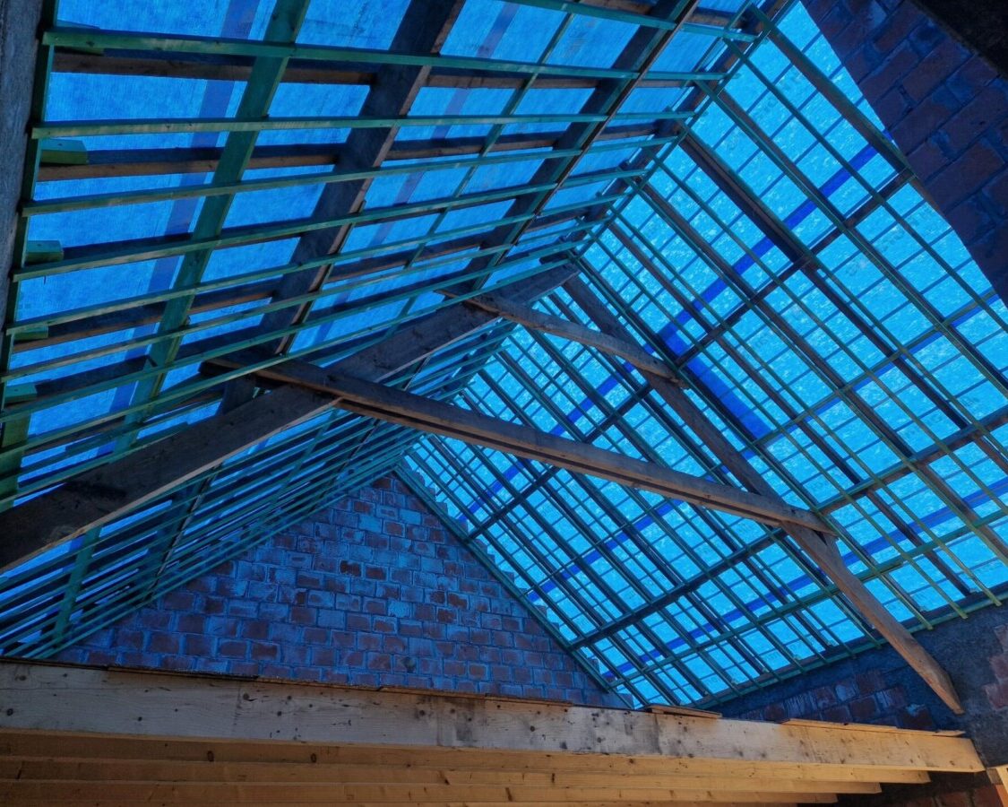 Rénovation de toiture avec la charpente en bois recouverte d'une bâche bleue