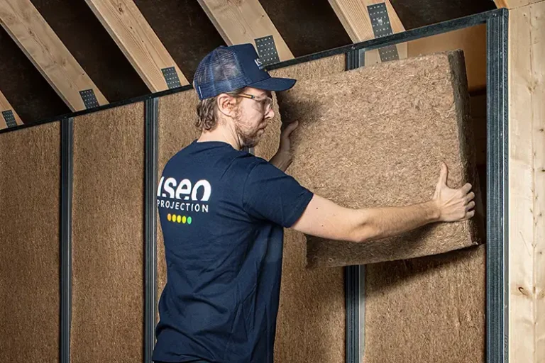 Ouvrier d'ISEO Projection en train de placer de l'isolant en fibre de bois sur le mur d'un grenier