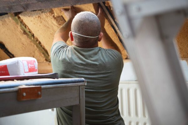 iseo-isolation-biosourcee-toiture Homme en train de placer de l'isolant en laine de bois sur une toiture
