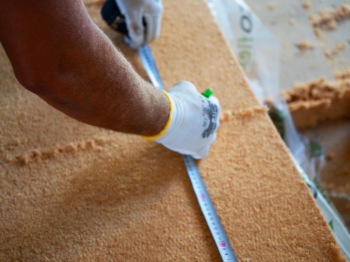 Ouvrier d'ISEO en train de découper de l'isolant biosourcé sur un chantier d'isolation de toiture