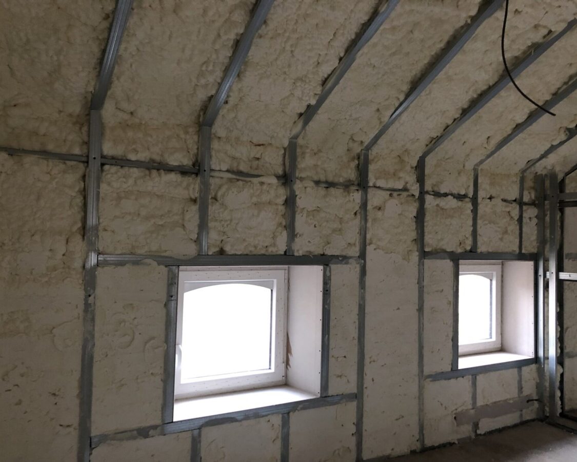 Mousse projetée sur un mur et un toit d'une maison à Hemptinne