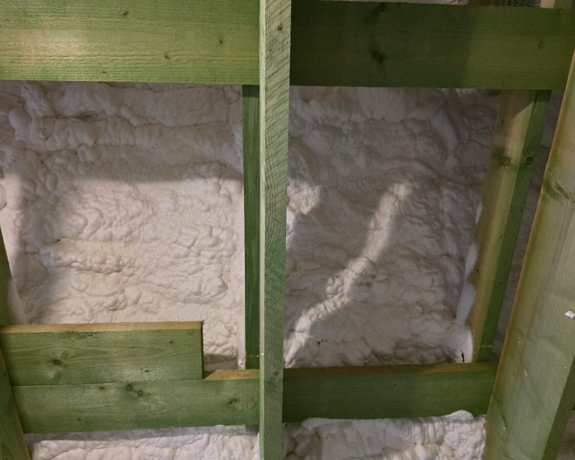 Isolant en mousse projetée entre des poutres en bois dans une toiture