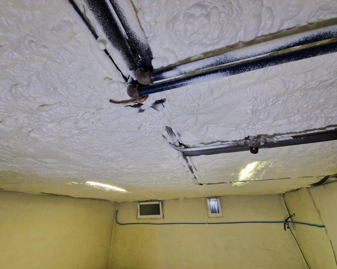Plafond de cave avec des tuyaux isolé avec de la mousse projetée