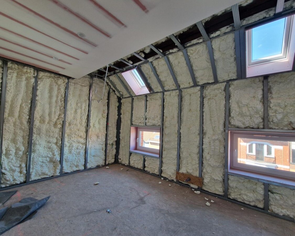 Combles isolés avec 17 cm de mousse polyuréthane H2O projetée sur les rampants et les murs d'une maison à Zaventem, ossature métallique et fenêtres de toit installées.