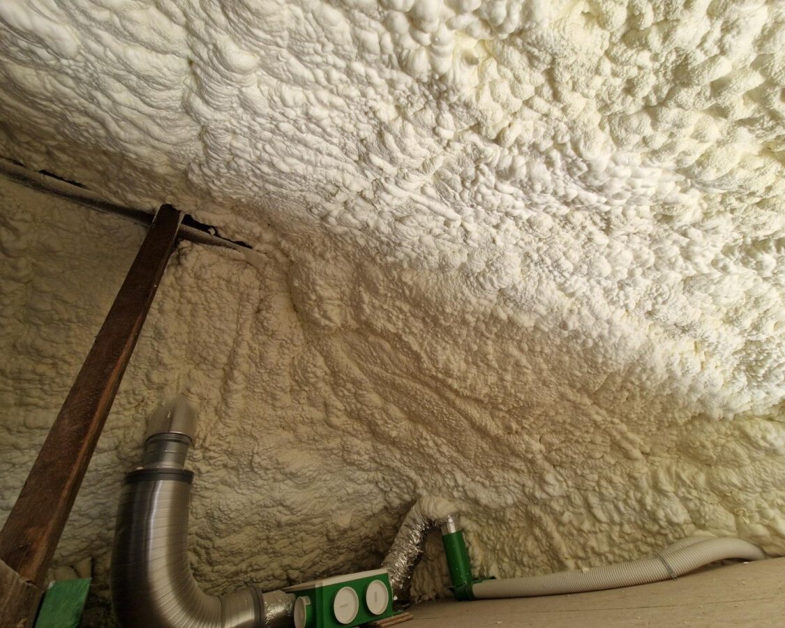 Isolation de plafond projetée à la mousse H2O dans une maison à Zaventem, avec réseau de ventilation double flux et gaines techniques visibles en sous-face.