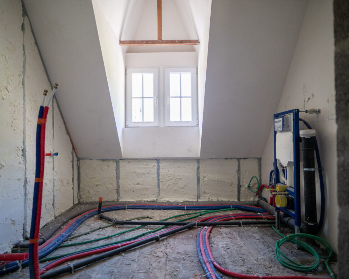 Salle de bain en cours de rénovation avec murs isolés par mousse polyuréthane projetée à cellules ouvertes, adaptée aux bâtiments anciens en pierre.