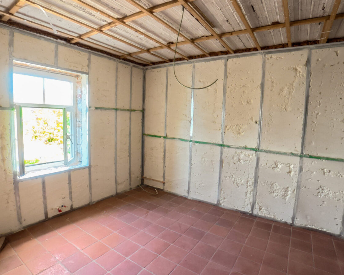 Chambre en rénovation avec isolation en mousse polyuréthane projetée sur les murs intérieurs, assurant une isolation continue sans pont thermique.