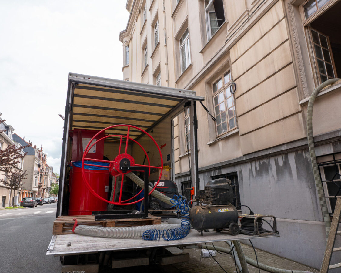 Matériel d’insufflation de ouate de cellulose installé au pied de l’immeuble pour isoler les murs d’un appartement en copropriété à Bruxelles.