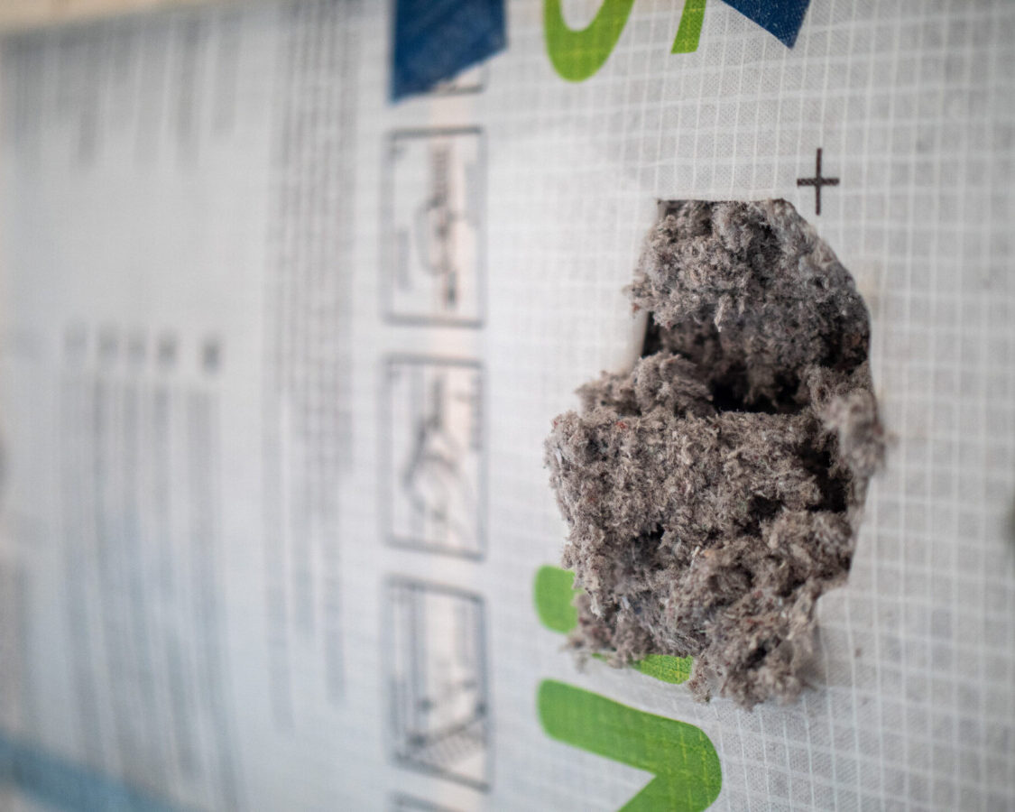 Gros plan sur la ouate de cellulose IQ3, isolant biosourcé utilisé pour améliorer les performances thermiques et acoustiques d’un appartement à Bruxelles.