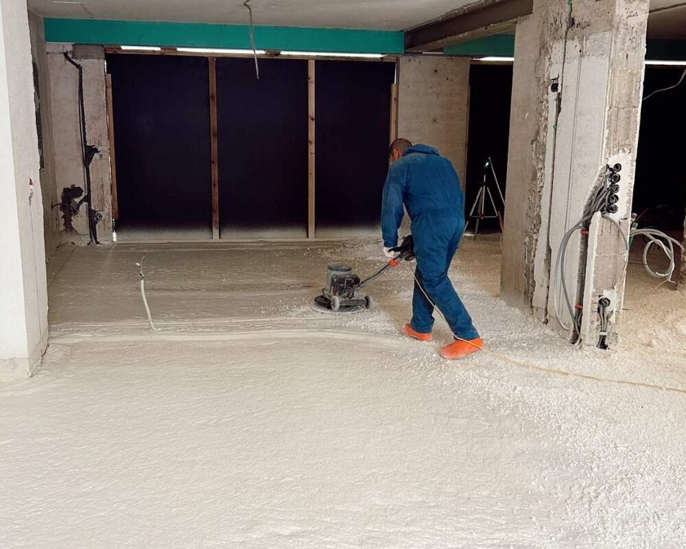 Ouvrier d'ISEO Projection qui tasse la mousse polyuréthane qu'il a projeté sur le sol d'une maison à Ringel