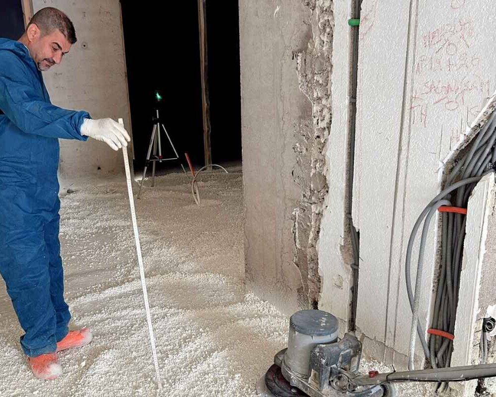Ouvrier d'ISEO projection qui mesure la hauteur de la mousse polyuréthane qu'il a projeté sur le sol d'une maison à Ringel