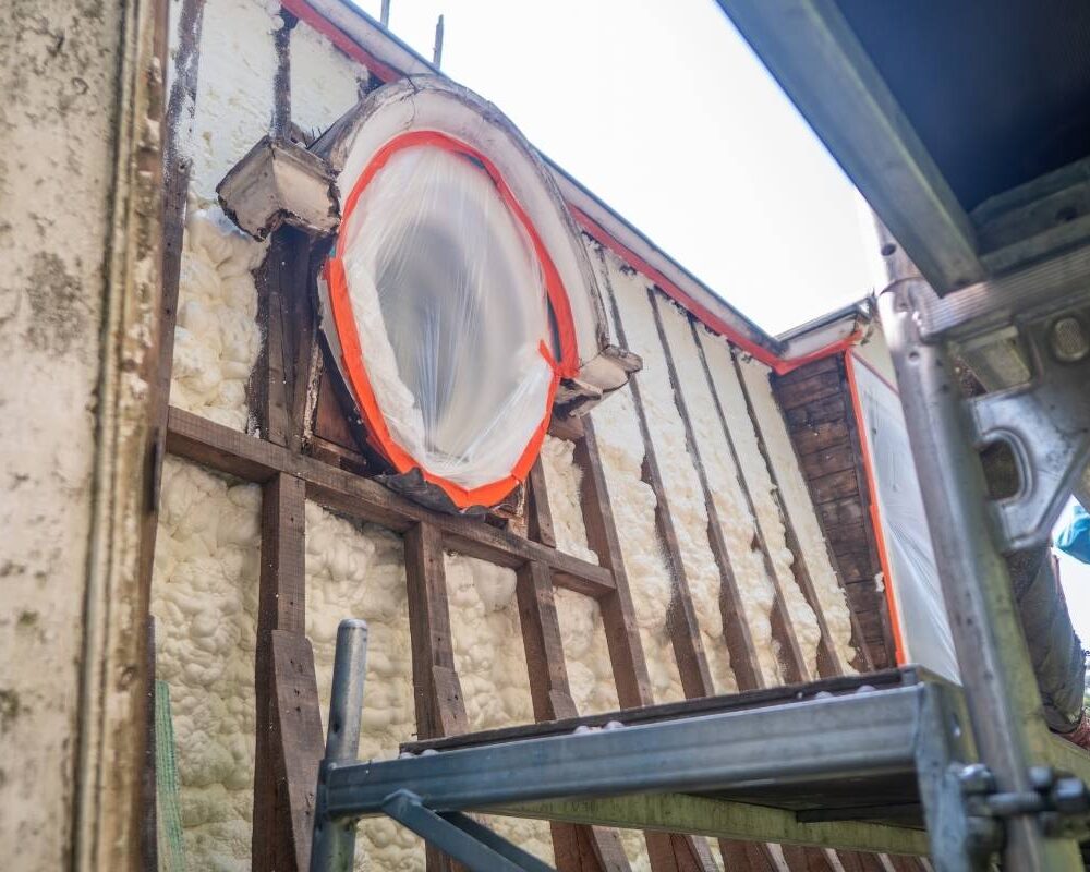 Chantier d'isolation en mousse projetée d'une toiture "à la Mansart" à Spa avec une lucarne